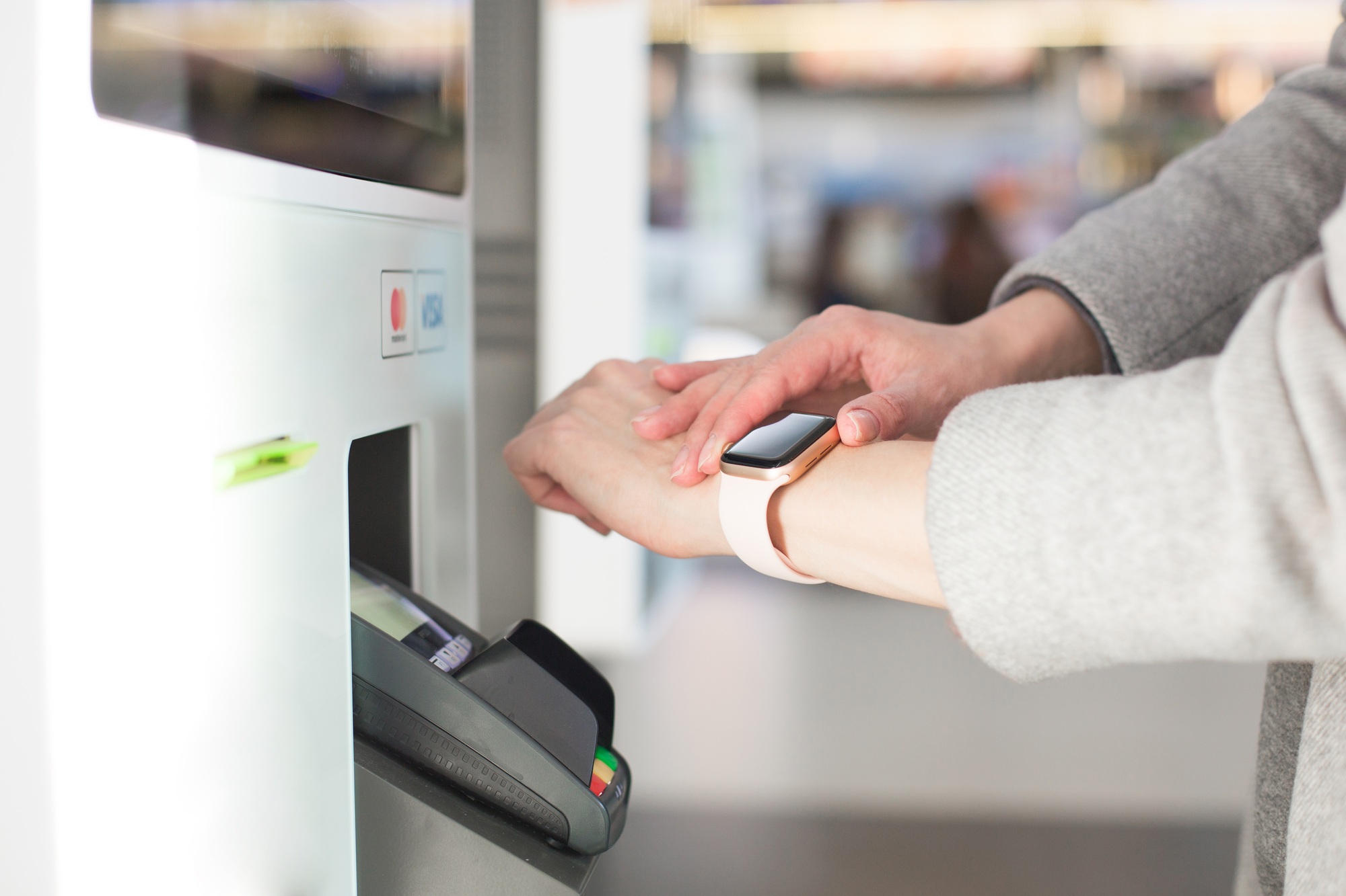 Woman paying at cafe with smart watch wirelessly on easy POS terminal